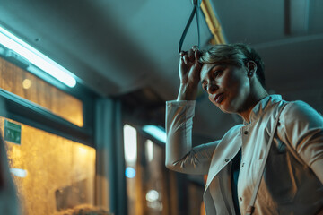 Woman standing on a bus at night exhausted after work