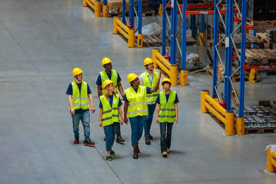 Warehouse workers walking and discussing the goods on the shelves