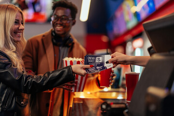 Cheerful couple buying movie tickets.
