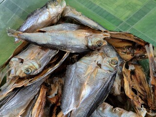 Close-up of a traditional Indonesian salted fish dish, showcasing its rich texture and vibrant...