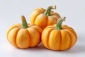 Obraz premium Three orange pumpkins with ribbed exteriors and green stems sit on a white surface with one pumpkin slightly behind the other two
