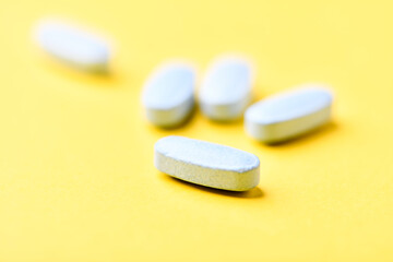 Multivitamin tablets on bright paper background. Close up. Copy space	