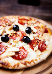 Pizza with salami and mozzarella cheese. Wooden background. Soft focus. Close up.	