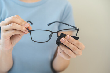 Cleaning glasses concept, close up hand of asian young woman hand holding frame of glass, use cloth...