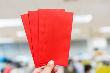 Four lucky money in red envelopes on man hand. New Year theme for advertising.