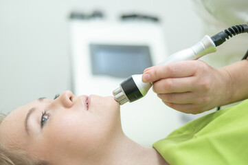 Caucasian woman undergoing radio wave RF lifting procedure in beauty salon. 