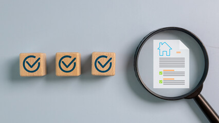 Magnifying glass focusing on house document with checklists next to wooden blocks with check marks....