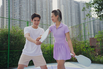 Asian friends practicing pickleball in an urban park setting, celebrating fun and fitness together...