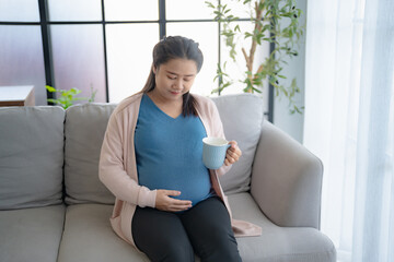 Obraz premium Pregnant asian woman drinking milk at home relaxation and Self-care Pregnancy drinking a glass of fresh milk mother mindfulness Positive life moment in pregnancy time