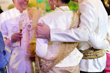 selective focus A man's hands are hugging a woman's shoulders from behind with love at a Thai wedding at a celebration party