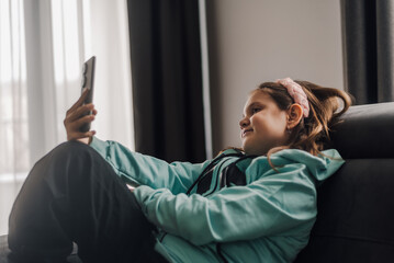 Smiling girl using smartphone on sofa at home