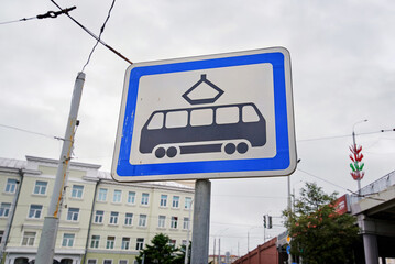 Road sign marking tram stop location stands tall against cloudy sky, urban public transit infrastructure and electric streetcar accessibility. Tram stop sign captured with cloudy sky background