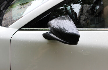 The rear view mirror is attached to the side surface of the car door after heavy rain