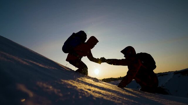 Travelers climb one after another on rock. Teamwork of business people. Climbers silhouettes stretch their hands to each other, climbing to top of hill. Team of businessmen, victory. Lend helping hand