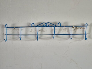 Wall-Mounted Blue Metal Hook Rack with Decorative Top and Signs of Use