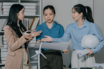 Fototapeta premium business women talking on cell phone Three young Asian female real estate agents meet to discuss selling a house in the office.