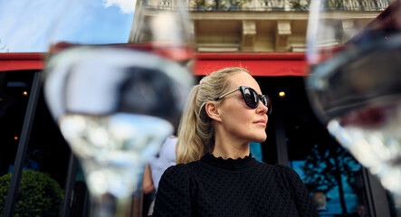 Elegant woman enjoying parisian cafe ambiance through wine glasses