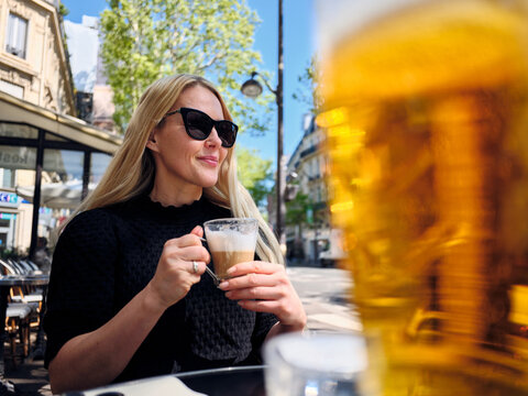 Tourist enjoying a cappuccino at a parisian outdoor caf&eacute;