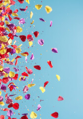 Fototapeta premium Colorful petals cascade down against a bright blue sky