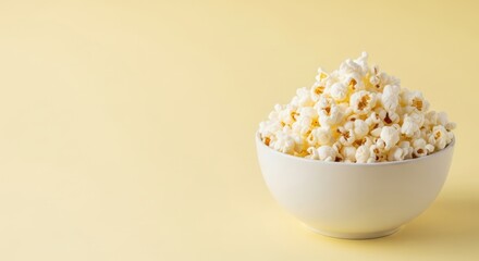 A bowl of fluffy popcorn on a pale yellow background perfect for movie night and snack food advertising