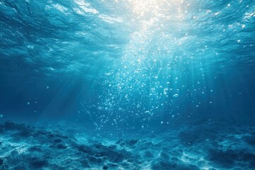 Sunbeams penetrate deep ocean water, illuminating rising bubbles and a rocky seabed
