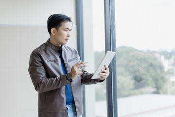 Young professional using modern technology for business management, enjoying natural light and city...