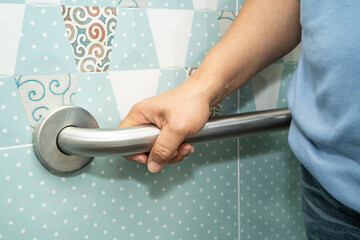 Asian elderly woman patient use toilet bathroom handle security in nursing hospital, healthy strong medical.