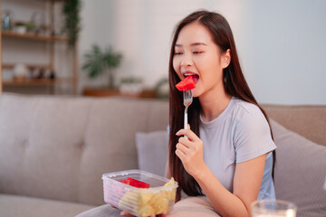 Young Asian woman enjoying a healthy fruit snack watermelon and pineapple promoting wellness and...