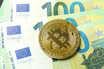 Close up of metal shiny bitcoin crypto currency coin on euro banknotes. Electronic decentralized money concept. 