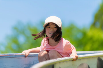 公園のローラー滑り台で遊ぶ笑顔の園児の女の子