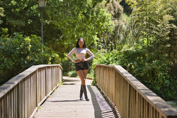 Young, beautiful, African woman, wearing a sweater, leather pants and boots, posing as a model in...