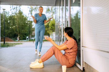 Healthcare workers engage in conversation outside building during sunny afternoon in urban park...