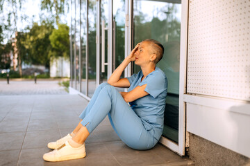 Health care worker takes a moment to rest outside the clinic during a busy day in the afternoon