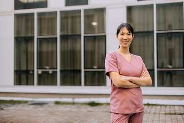 Healthcare professional stands confidently outside modern medical facility during a sunny day