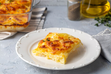 Potato gratin - graten (baked potatoes with cream and cheese) with rosemary and forks (Turkish name; Kremali patates)