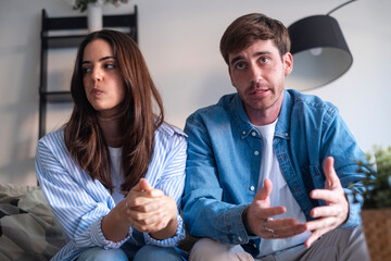 Couple sitting tensely on a sofa during a therapy session, facing serious relationship issues....