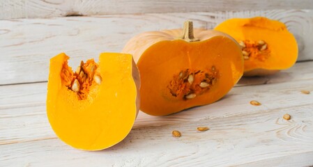 Pumpkin slices with seeds on white wooden background. Healthy, seasonal, vegetarian food.