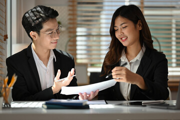 Two Business analysts exchanging insights and analyzing financial data in a bright, collaborative workspace