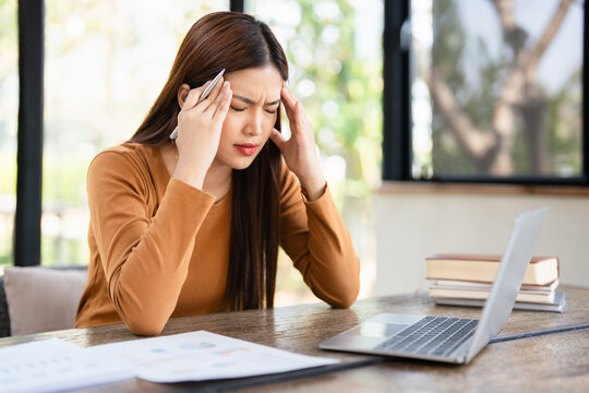  Stressed tired woman in pain having strong terrible headache attack after computer laptop work, fatigued exhausted girl suffering from chronic migraine massaging temples to relieve head ache tension