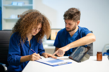 Doctor guides female patient to complete medical registration form. Concept of healthcare paperwork, consent,