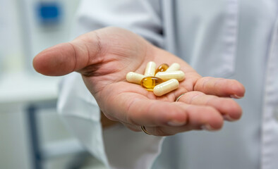 Hand holding capsules or pills medicine healthcare treatment in a medical setting.