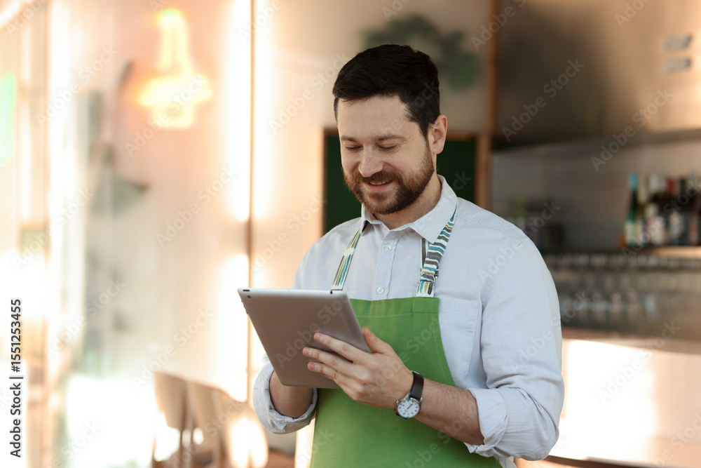 Poster smiling business owner working with tablet in his cafe. space for text