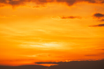 Dramatic orange and yellow sky with dark clouds at sunset