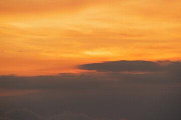 Dramatic orange and yellow sky with dark clouds at sunset