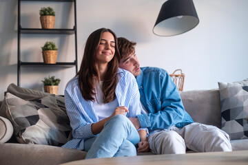 Young couple sitting on the sofa making peace after an argument. Reconnecting emotionally, sharing...