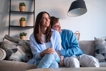Young couple sitting on the sofa making peace after an argument. Reconnecting emotionally, sharing...