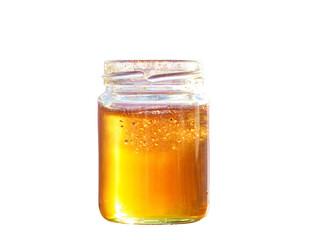 Honey in a glass jar on white background showing sweet golden liquid and food freshness