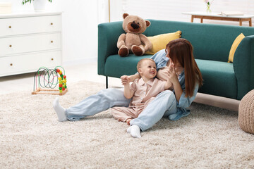 Mother spending time together with her happy son on floor at home
