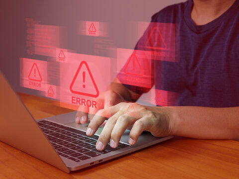 Person typing on laptop with multiple red error warning signs floating above keyboard, indicating computer malfunction or software issue causing frustration and urgency