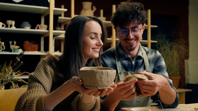 Caucasian woman man teacher student in pottery workshop handmade craft hobby potter teaching sculpture ceramics clay modeling couple date girl guy have fun laughing creating crockery in art studio